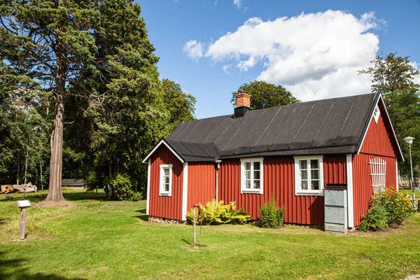 田舎の木々の下に黒い屋根のある美しく居心地の良い木造の赤い家 — ストック写真