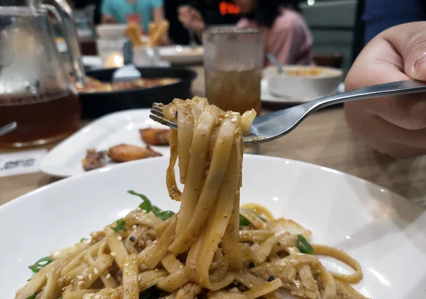 Zbliżenie Włoskiego Makaronu Fettuccini Białym Talerzu Podniesione Widelcem Rozmytym Tle — Zdjęcie stockowe