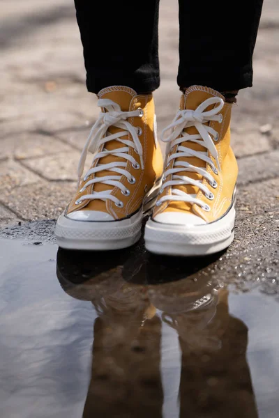 Birikintisinin Yakınındaki Sarı Yüksek Topuklu Spor Ayakkabıların Dikey Yakın Çekimi — Stok fotoğraf