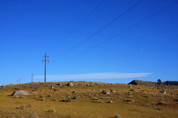 Uma Fileira Postes Elétricos Sobre Campo Rochoso Campo — Fotografia de Stock