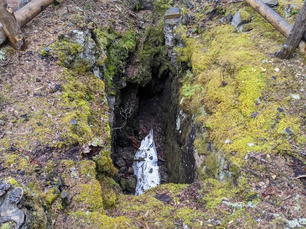 地面に苔の成長と大きく深い穴に落ちた白い岩 — ストック写真