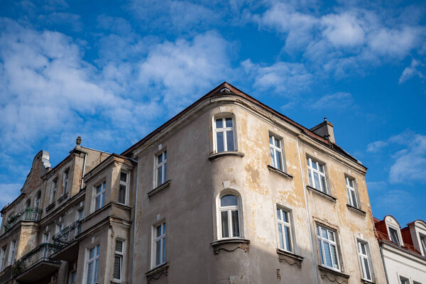 A closeup shot of an old residential building against a blue cloudy sky