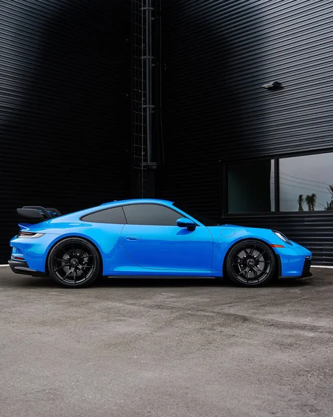 Modern mavi bir Porsche 911 GT3 spor arabasının dikey yan görüntüsü.