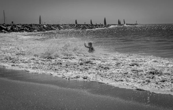 Серый Снимок Человека Окруженного Плескающимися Волнами Пляже Калифорнии — стоковое фото