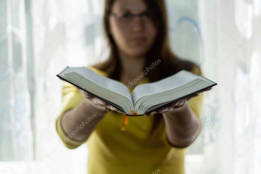 A close up of white-skinned young woman holding books
