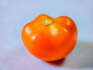 Beyaz bir yüzeyde taze kırmızı sulu bir domatesin yakın plan çekimi.