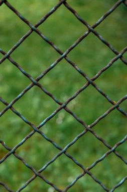 Bulanık bir arka planda paslı bir çitin dikey çekimi.