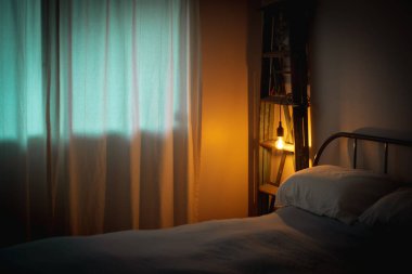 Yatak odasının içinde bir ampul var. Akşam yatağın yanında.