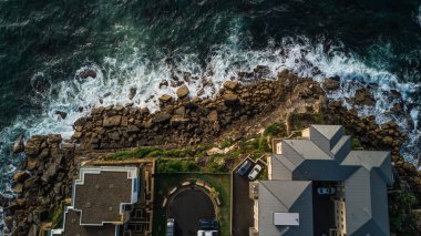 Kıyıya yakın dalgaların ve taşların kuş bakışı görüntüsü.