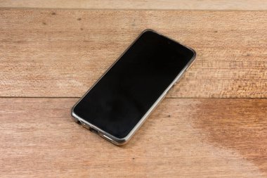 Ahşap masadaki eski siyah akıllı telefonun yakın çekimi.