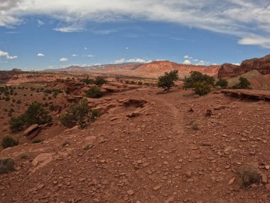 Kaya oluşumları ve kuru bitki örtüsüyle ıssız bir kırsal alanın manzarası.