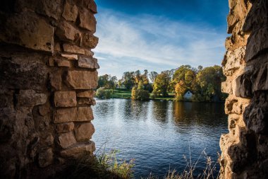 Tuğla duvarlar arasında sonbahar ağaçları olan güzel bir göl manzarası