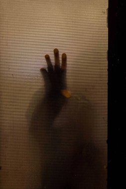 Kahverengi cam kapıya dokunan bir adamın dikey görüntüsü.