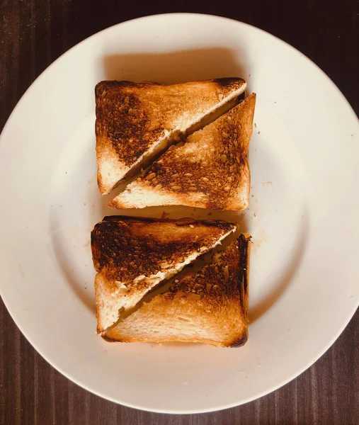 Beyaz tabakta yarım dilimlenmiş Fransız tostlarının üst görüntüsü.