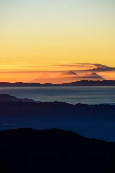Pionowe Ujęcie Jedwabnych Chmur Pomiędzy Górami Podczas Zachodu Słońca — Zdjęcie stockowe