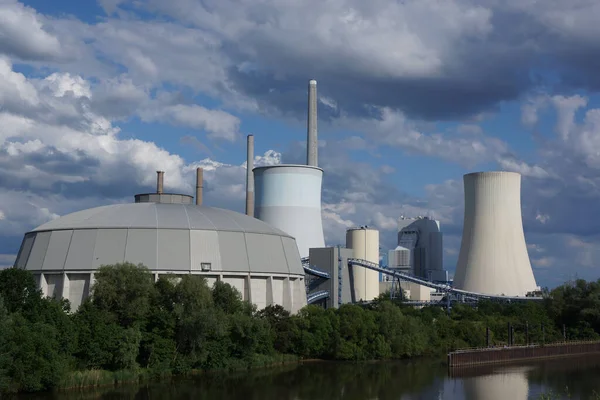 Staudinger coal-fired power plant on the river Main near Hanau, Germany in evening light against a turbulent sky. Coal storage in the foreground.