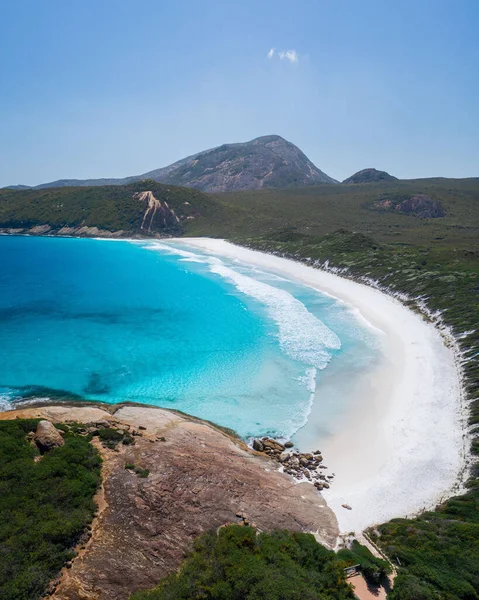 Bereketli yeşil doğayla çevrili cennet gibi beyaz kumsalın dikey bir görüntüsü.