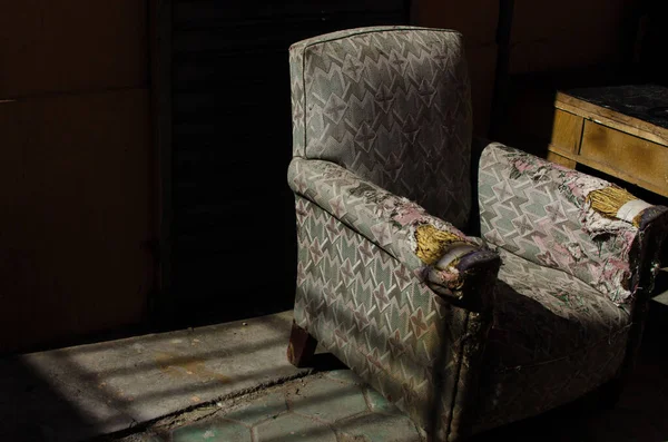 A closeup shot of an old damaged sofa with floral patterns in the room