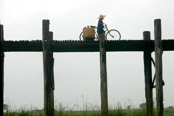 木製の橋の上に自転車に乗る大きな太陽の帽子の女性の低角度ショット — ストック写真