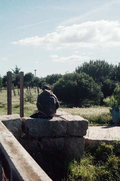 Вертикальный Снимок Мальчика Сидящего Каменной Стене Солнечный День — стоковое фото