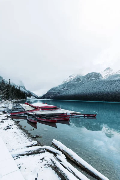 Вертикальный Снимок Ледяного Озера Луиза Альберта Красными Лодками Дне Снежных — стоковое фото
