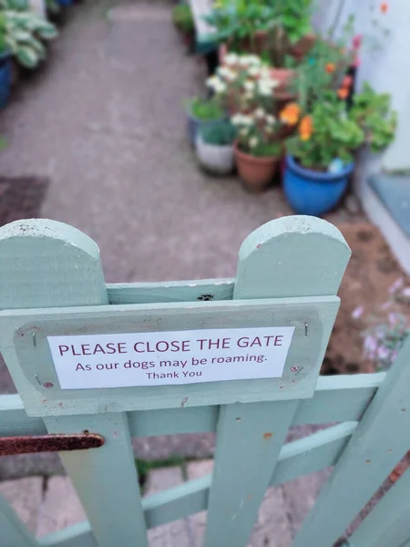看板の付いたミントカラーの木製ゲートのクローズアップ写真 ゲートを閉めてください と鉢植えを背景にしてください — ストック写真