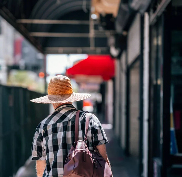 帽子をかぶって青い背景の街を歩く若い男 — ストック写真