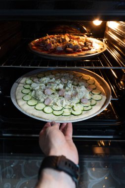 Sosis, salatalık ve peynirli ev yapımı iştah açıcı bir pizzanın pişirme süreci.