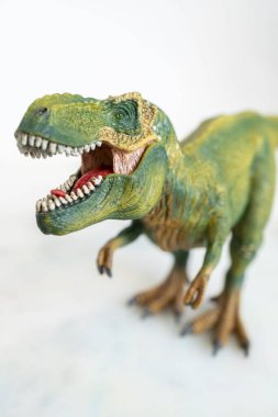 Beyaz arka planda Schleich marka yeşil Tyrannosaurus Rex oyuncak dinozor heykelciği.