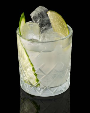 Siyah arka plan üzerinde limon dilimleri olan bir bardak kokteylin yakın çekimi.