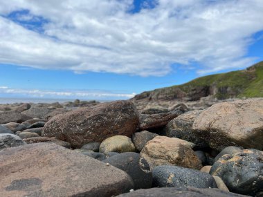 Mavi bir gökyüzünün altında bulanık bir zemindeki taşları.