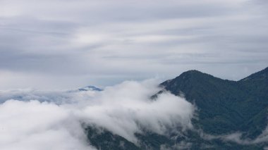 Slovenya, Kamnik-Savinja Alpleri, Büyük Çayırlık Platosu 'ndaki bulutların altındaki tepelerin güzel manzarası