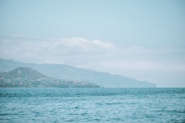 Mavi gökyüzünün altında mavi su ve dağlarla Madeira sahilinin büyüleyici bir görüntüsü.