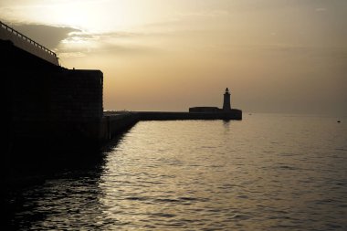Gün batımında bir deniz fenerinin silueti