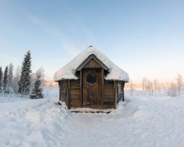 Karla çevrili küçük ahşap kulübe. Laponya, Finlandiya.