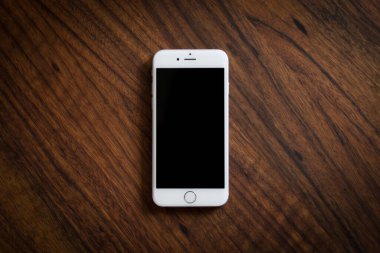 Tahta masadaki beyaz akıllı telefonun bir şablonunun üst görüntüsü