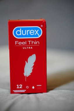 Durex markasının yakın plan fotoğrafı. Kırmızı kutuda ince prezervatifler, bulanık bir arkaplan.