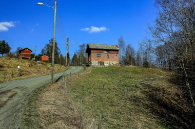 Binaların arka planında çimlerle çevrili asfalt bir yol manzarası