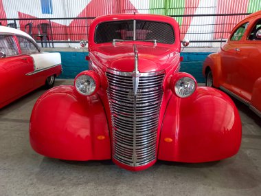Eski kırmızı Chevrolet Chevy Master Coupe 1938 'de GM tarafından bir depoda. Sokak arabası. Ön manzara. Izgara yap. Krom. Expo Fierro 2022 Klasik araba şovu