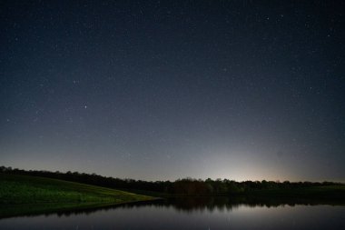 Yıldızlı gece gökyüzünün altında sakin bir göl manzarası