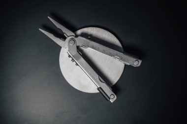 Kerpeten, bıçak ve diğer aletlerle birlikte teknik bir çoklu aletin detaylı ürün fotoğrafı. Black Metal ve ahşap arka planda paslanmaz çoklu araç.