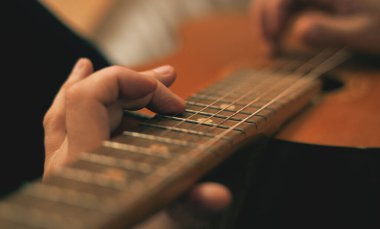 Akustik gitar çalan ellerin yakın çekimi.