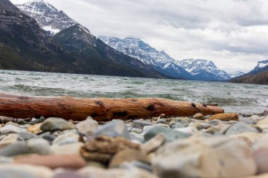 Bulutlu bir günde dağların arka planında kayalık bir sahilin alçak açılı yakın plan çekimi.
