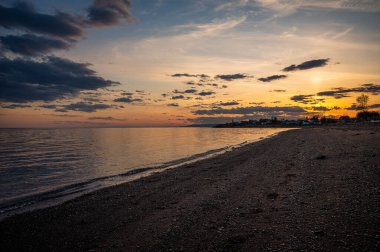 Sahilde canlı renklerle dramatik bir gün batımı.