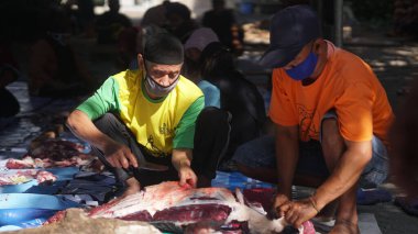 Maskeli iki Müslüman bayram kutlaması için bir hayvanın derisini yüzüyor.
