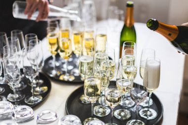 Bir düğün resepsiyonunda kadehlere dökülen sığ bir şampanya odağı.