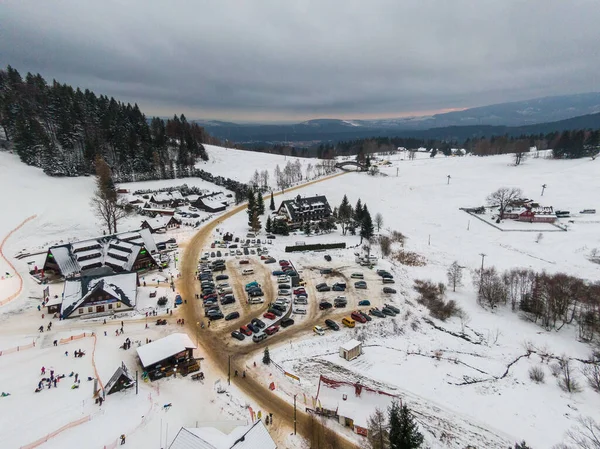 Gün batımında karla kaplı bir tepenin üzerindeki küçük bir şehrin hava manzarası.