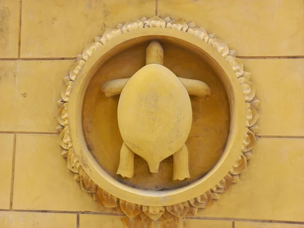黄色の壁に円の枠を持つ亀の彫刻 — ストック写真