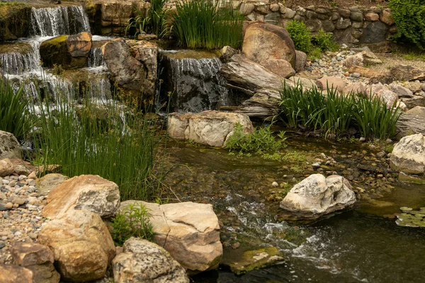 緑の芝生に覆われた岩を流れるカスケードの景色 — ストック写真