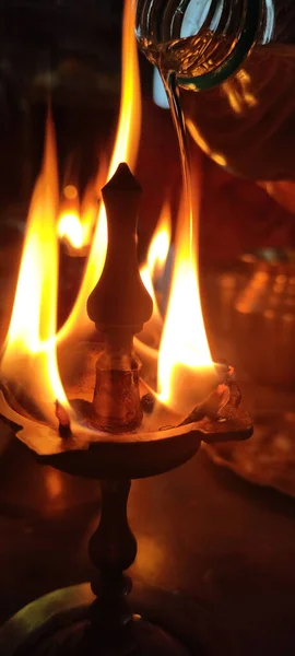 A vertical shot of a Diwali Oil Lamp and oil pouring process